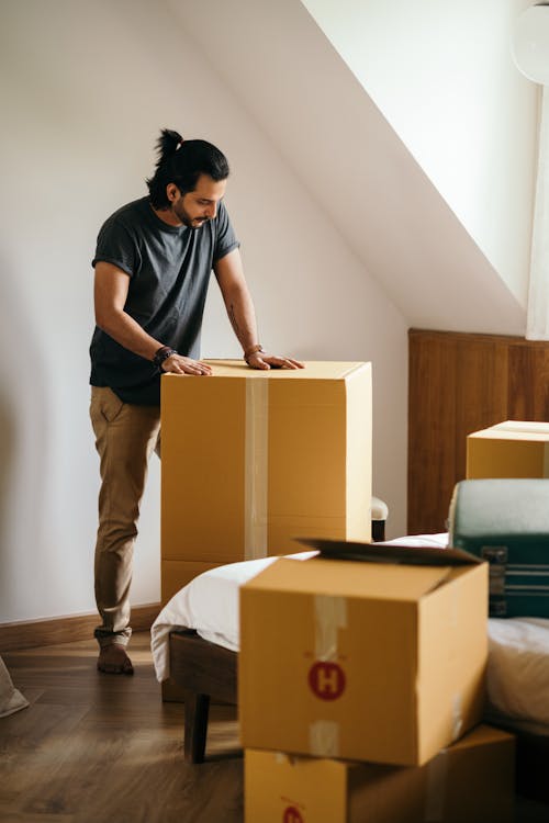 Young man packing cardboard boxes at home