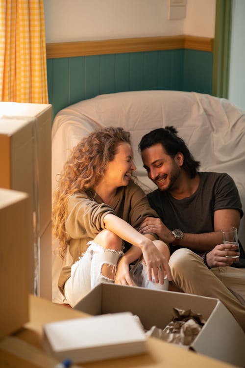 Happy couple laughing while embracing each other among carton boxes