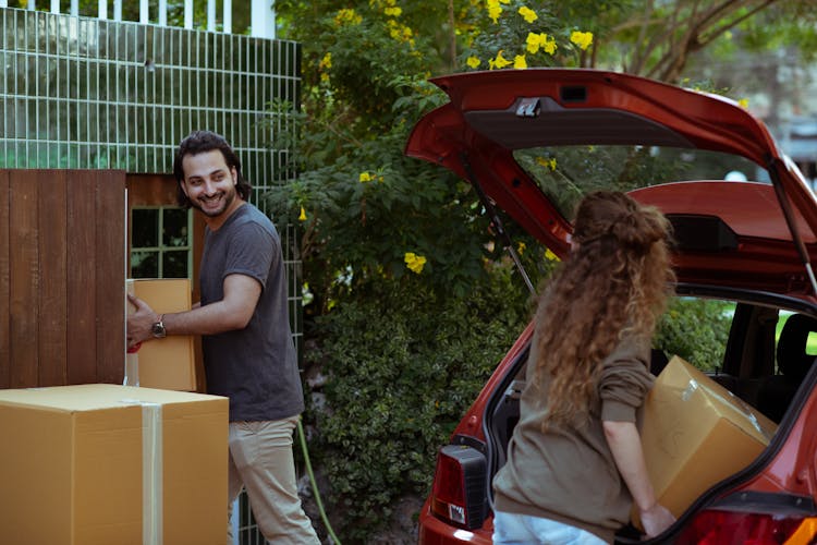 Couple Moving Boxes From Car Trunk To New House