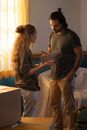 Couple talking in new house room with moved personal items