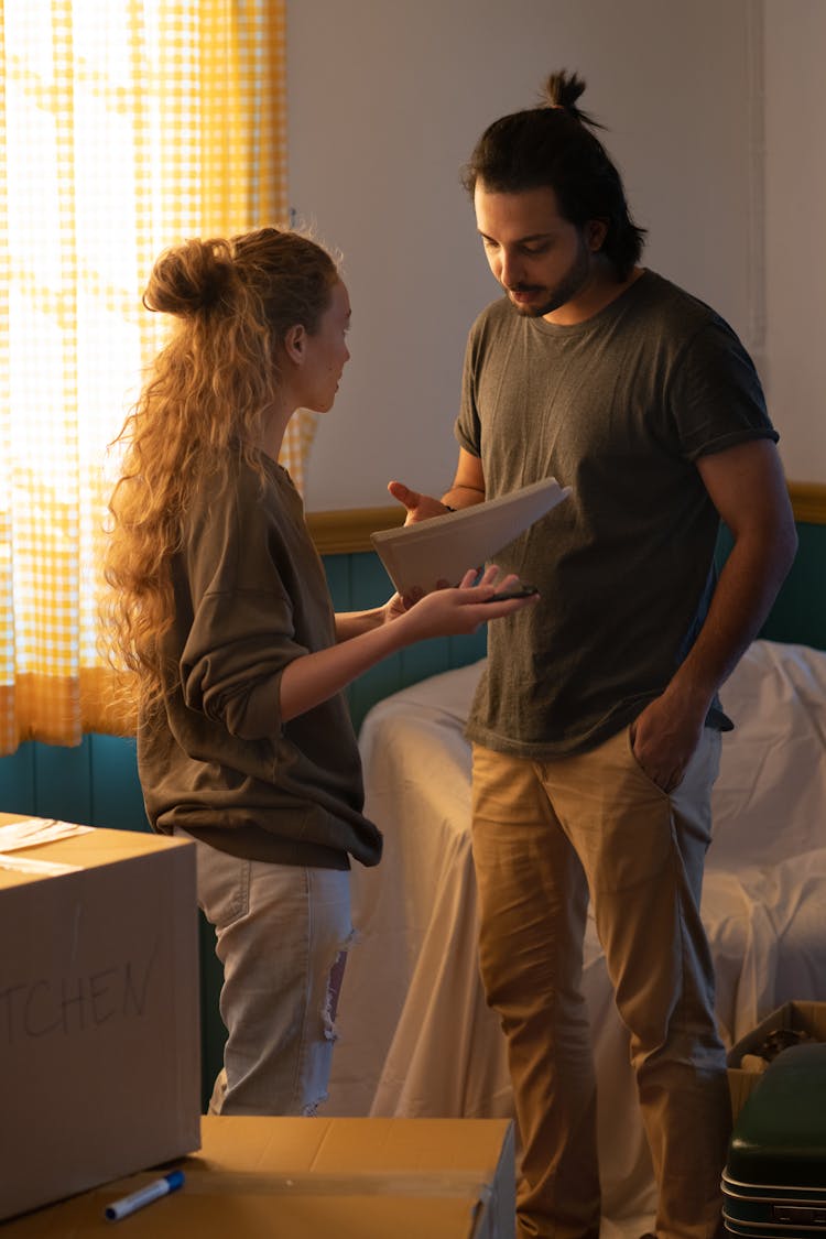 Couple Talking In New House Room With Moved Personal Items