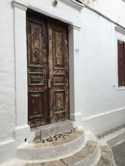 Explore the charm of an ancient wooden doorway on a white facade in Lindos, Greece.