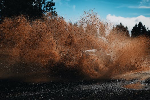 An off-road vehicle splashes through muddy terrain, showcasing power and motion in the countryside.