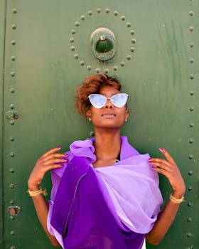 Fashionable woman in purple scarf poses confidently against a green door, exuding modern elegance.