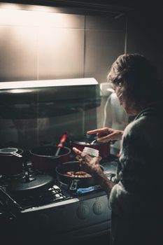 A person cooking dinner in a home kitchen, captured from behind.