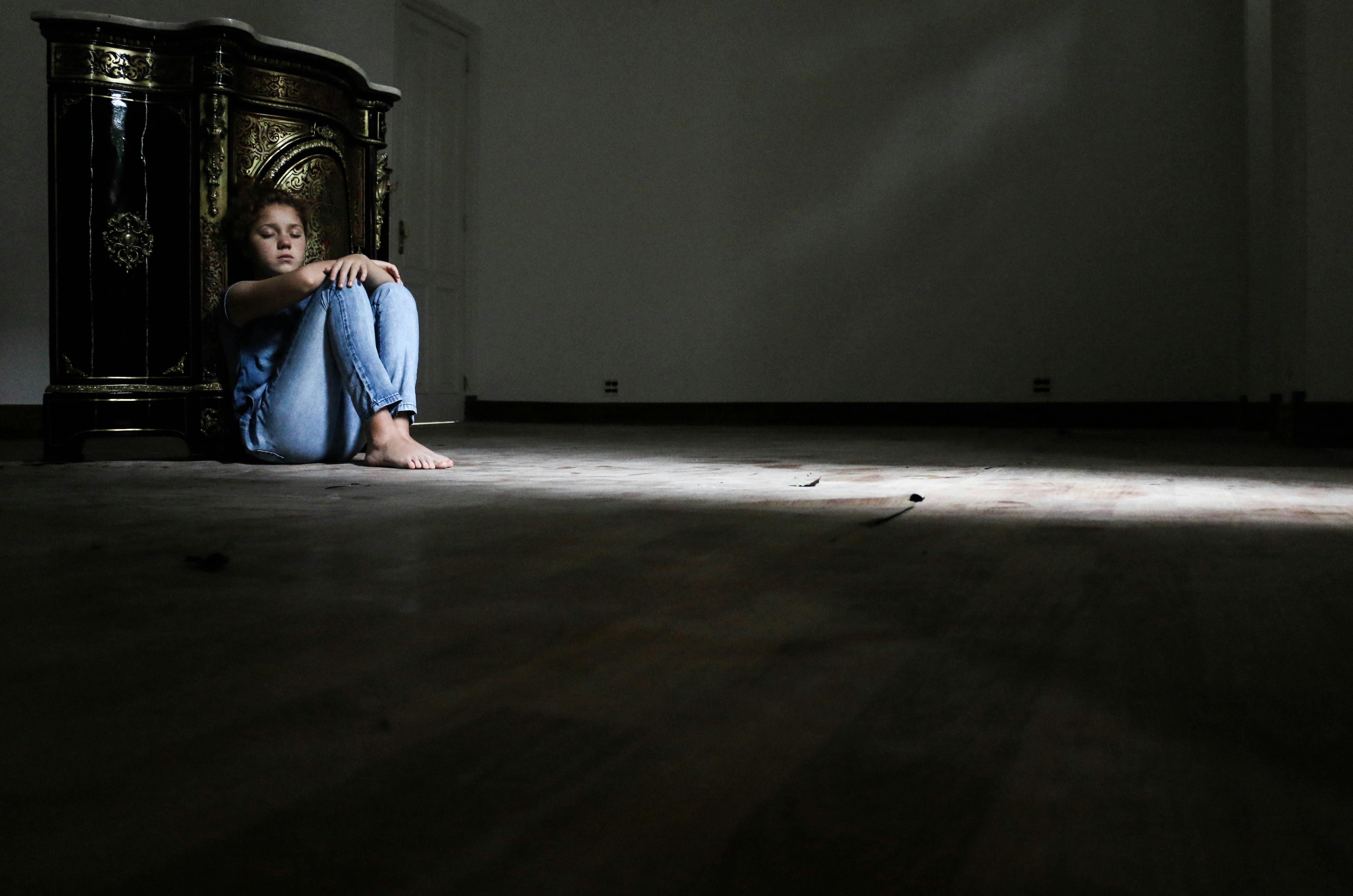 一个女人独自坐在黑暗的房间里，凸显了孤独和内省