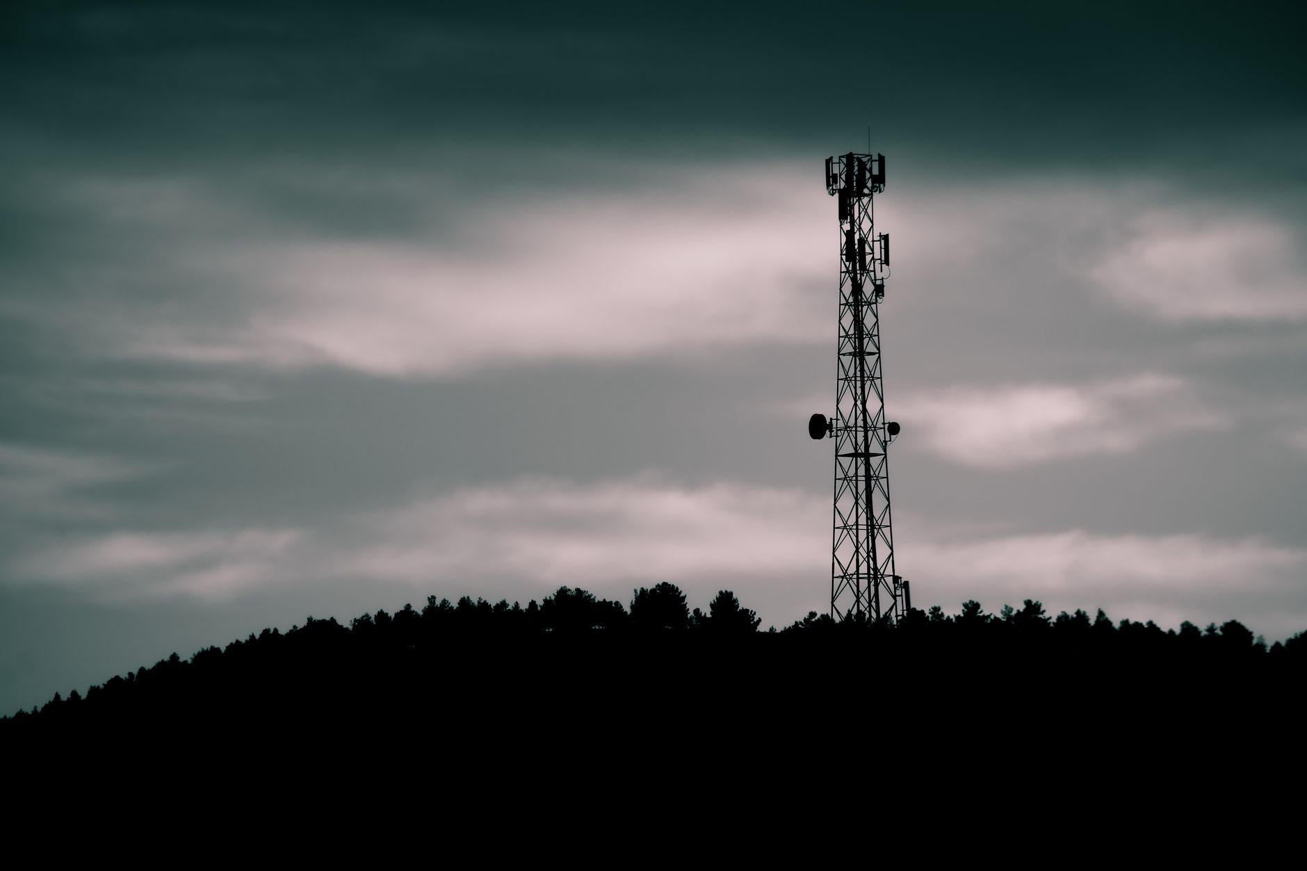 Dramatic silhouette of a telecommunication tower against a dusk sky, illustrating modern technology.