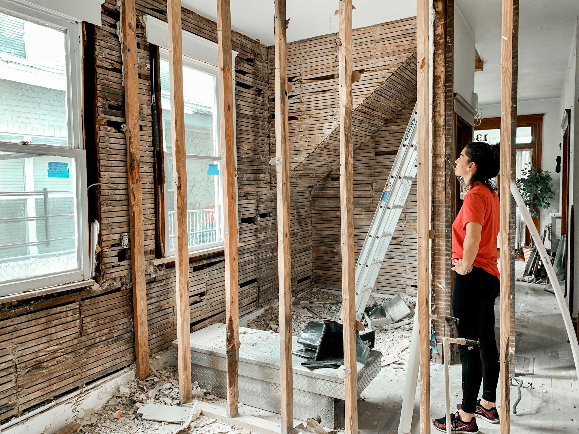 A woman inspects the progress of a home renovation project indoors, observing the construction site.