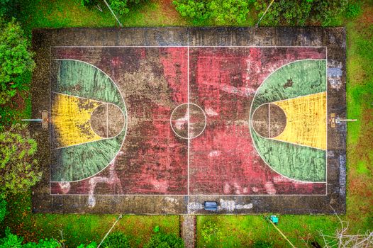 Vibrant aerial view of an old basketball court surrounded by green trees in Banten, Indonesia.