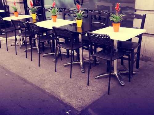 Free Charming outdoor bistro setup with colorful flowers and empty tables awaiting diners. Stock Photo