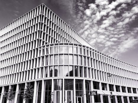 这是一张黑白照片，展示了一座具有玻璃立面和独特设计的现代建筑