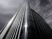 低角度镜头下，多云天空映衬着一座玻璃立面的时尚现代摩天大楼