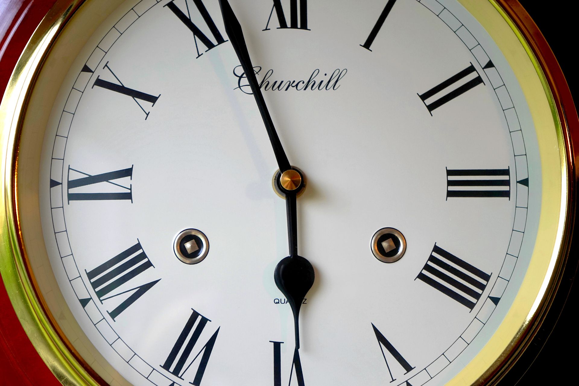 Close-up of a vintage clock face with roman numerals and gold trim, displaying classic design and elegance.