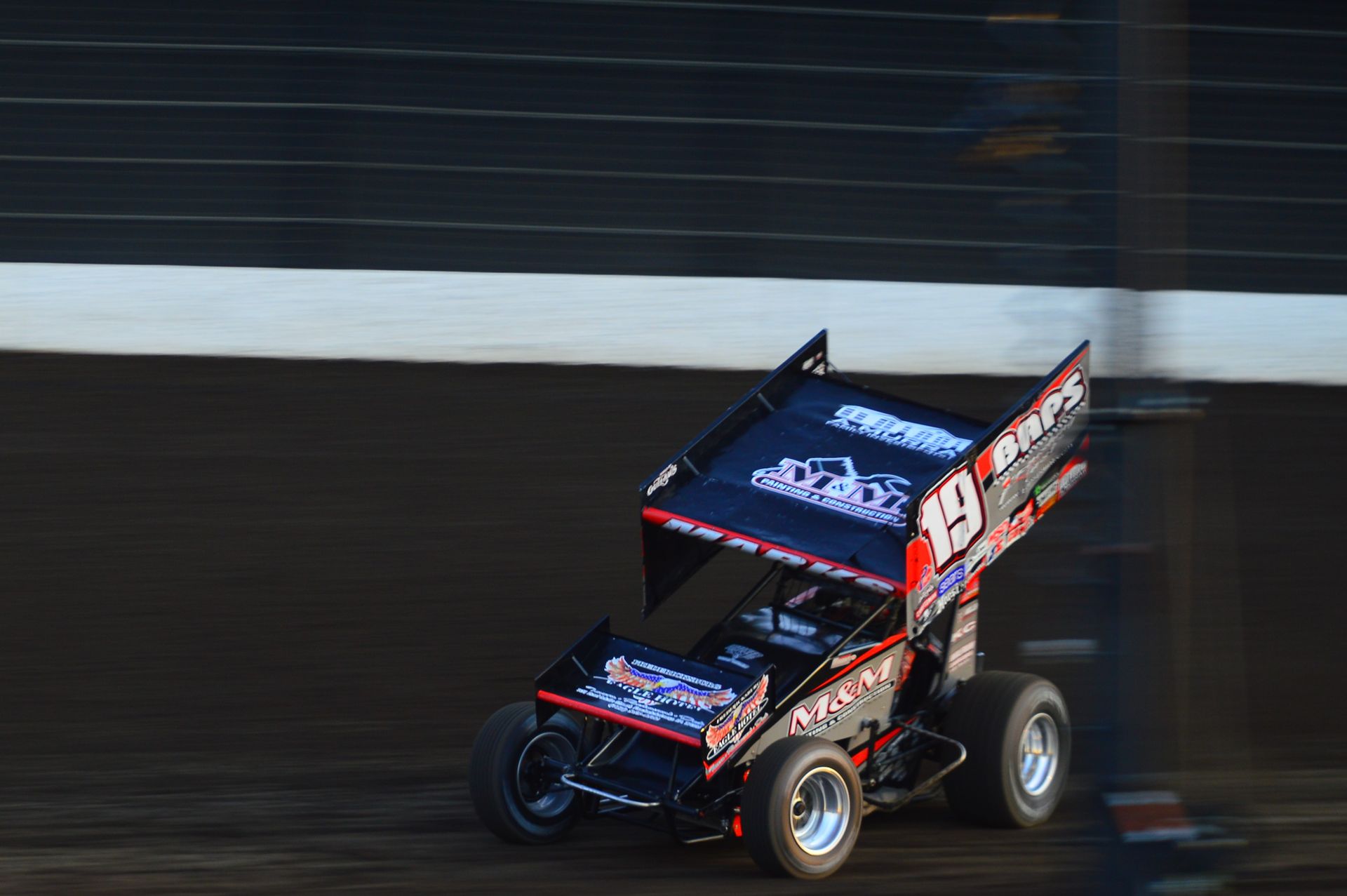 Contemporary sprint car driving fast along narrow stadium track during racing marathon