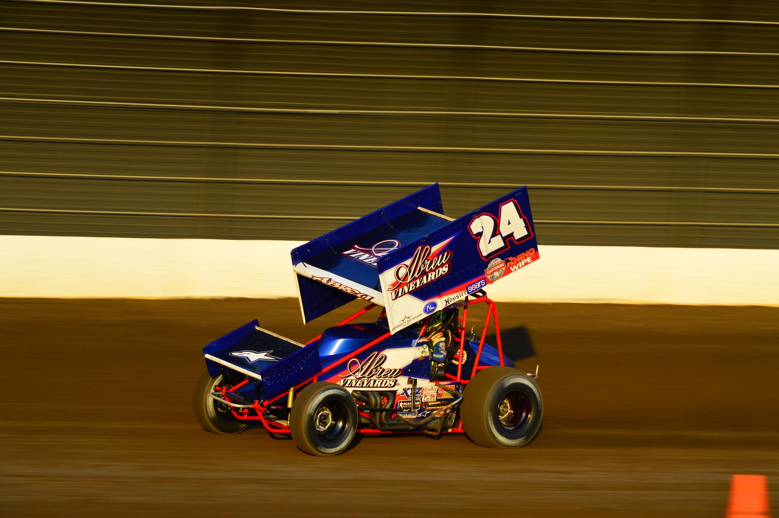 Sprint car kicking dirt on a clay oval at night