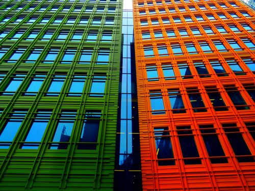 Free Striking modern architecture with green and orange facades featuring reflective glass windows. Stock Photo