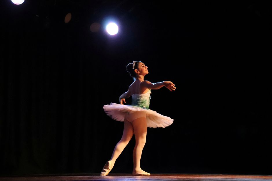 Student performing on stage under spotlight