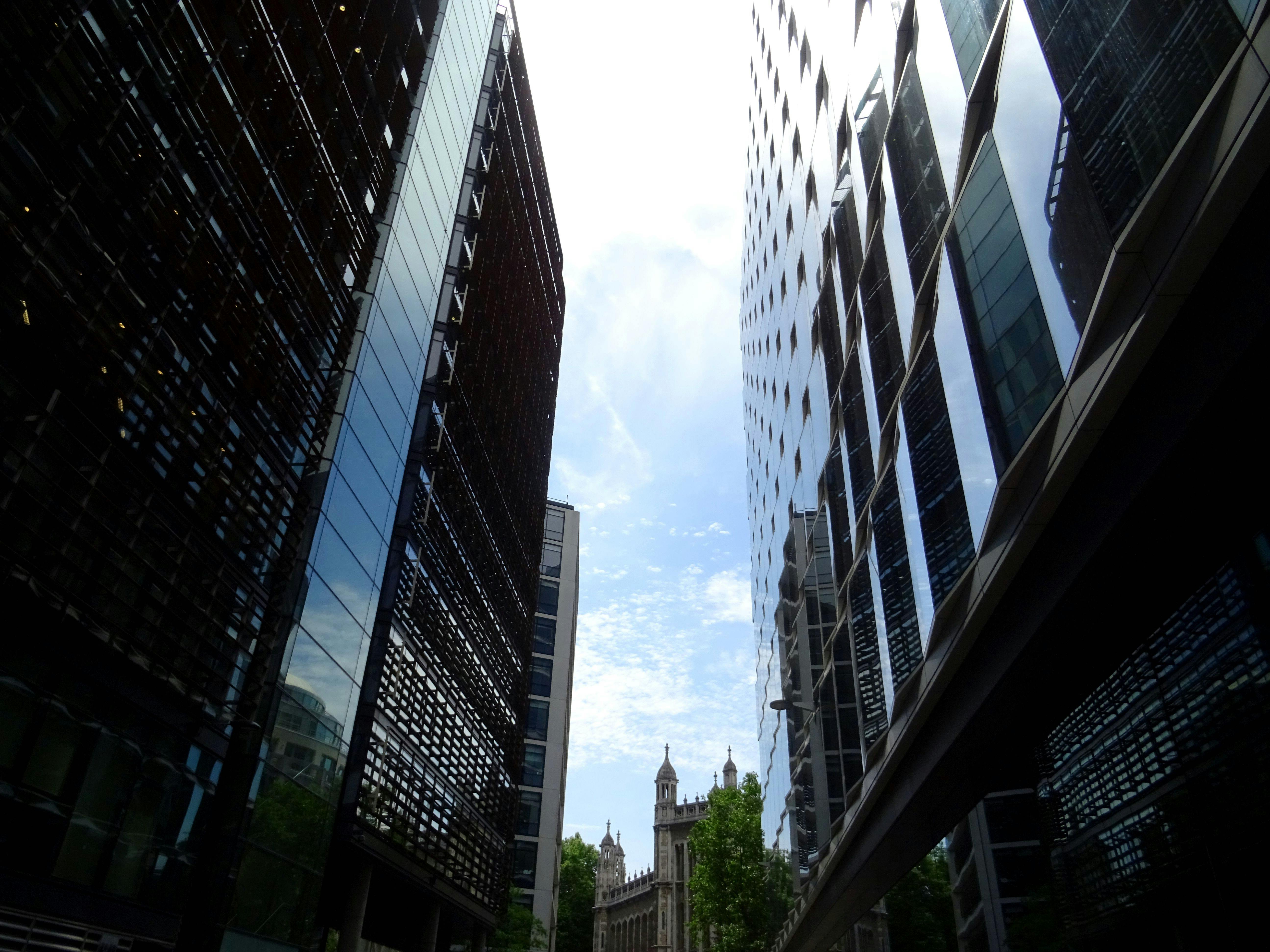 在繁华的城市地区，从低角度仰望高耸的反光摩天大楼和明亮的天空