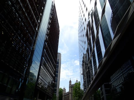 在繁华的城市地区，从低角度仰望高耸的反光摩天大楼和明亮的天空