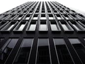 低角度拍摄的带有玻璃窗和钢立面的未来主义摩天大楼