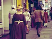 身着历史服装的人们走在城市街道上，营造出复古的氛围