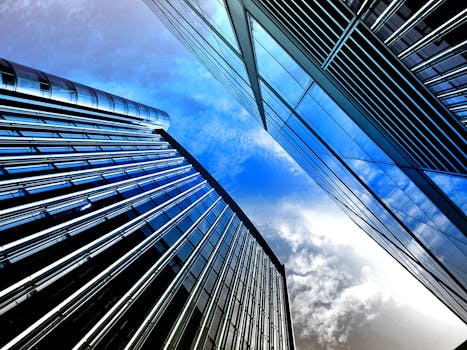 Low angle view of modern skyscrapers with reflective glass against a bright blue sky.