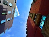 从现代摩天大楼下方俯瞰，城市景观壮丽，直抵清澈的蓝天