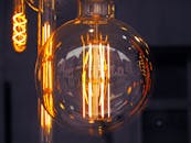 一个发光的老式灯泡特写，映出城市建筑的景观