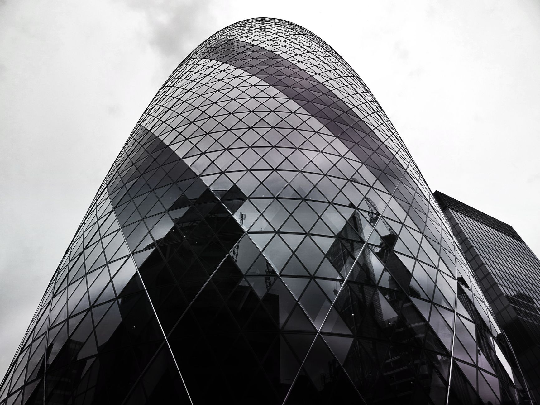 Modern architectural marvel, the Gherkin, stands tall against a cloudy London sky.