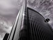 低角度视角下的现代摩天大楼，反光玻璃映衬着戏剧性的天空