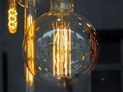 爱迪生风格灯泡的特写镜头发出温暖的光芒，映照着城市建筑