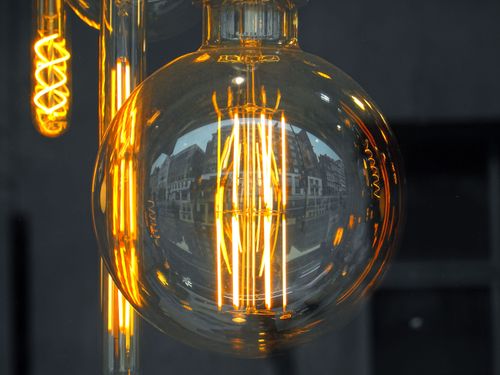 Free Close-up of an Edison style light bulb reflecting urban architecture, glowing warmly. Stock Photo