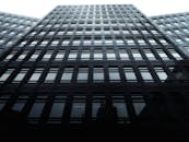 低角度镜头拍摄的城市环境中一座带有玻璃立面的现代摩天大楼