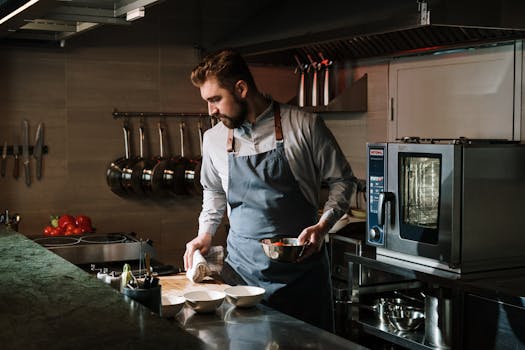 Male chef in a restaurant kitchen preparing a dish, showcasing culinary skills and expertise.