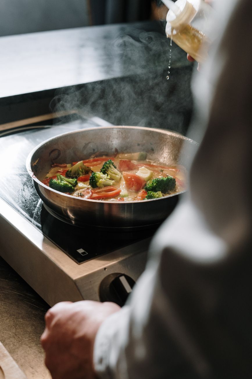 Steam lifting off just-cooked greens in a kitchen pan, the kind of moisture Stone says home cooks misread as blandness.