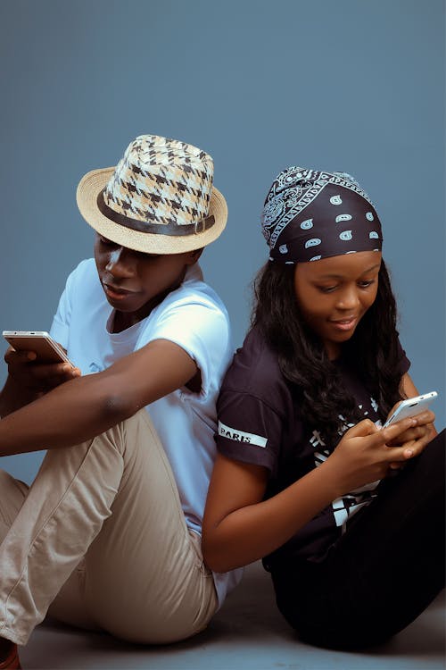 Man and Woman Sitting while Using Cellphones