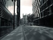 一条宁静的城市街道上，现代与历史建筑倒映水中，鹅卵石小路蜿蜒其间