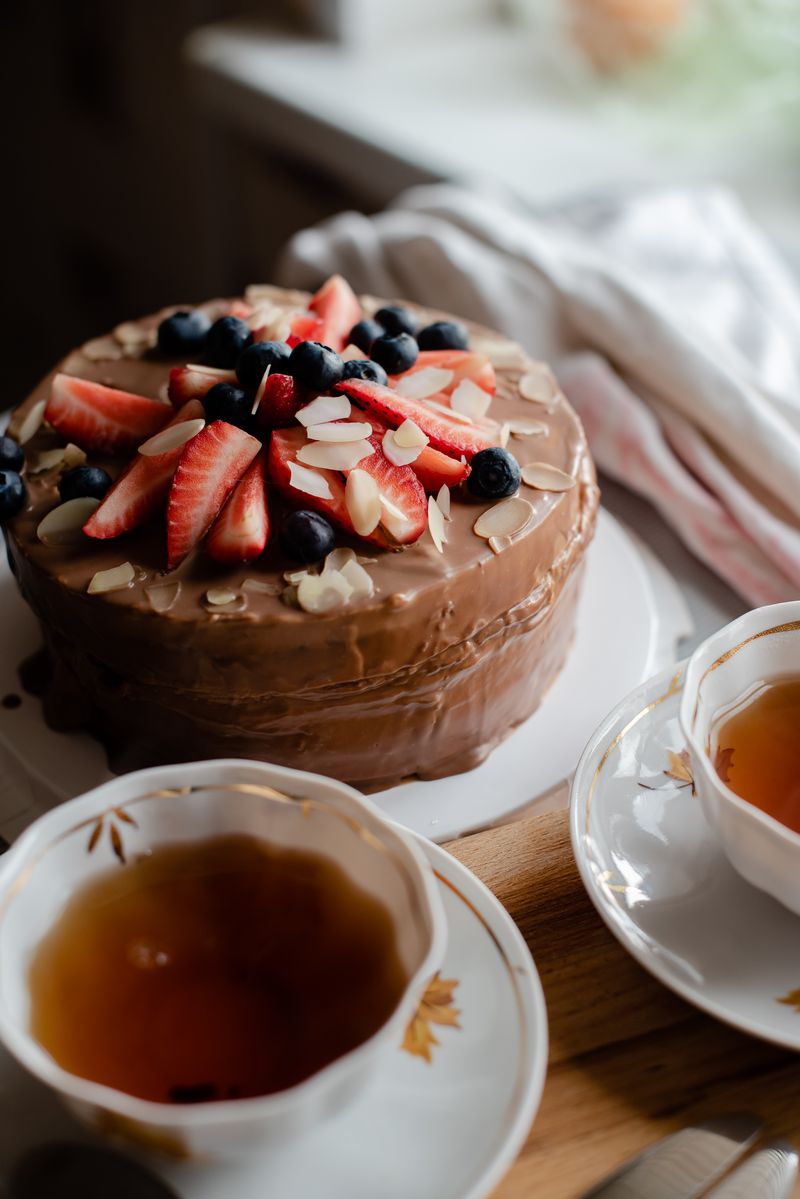 Round chocolate layer cake topped with fresh strawberries, blueberries, and almonds