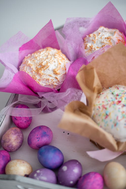 From above of colorful eggs and delicious cakes wrapped in decorative paper in gift box during Easter celebration