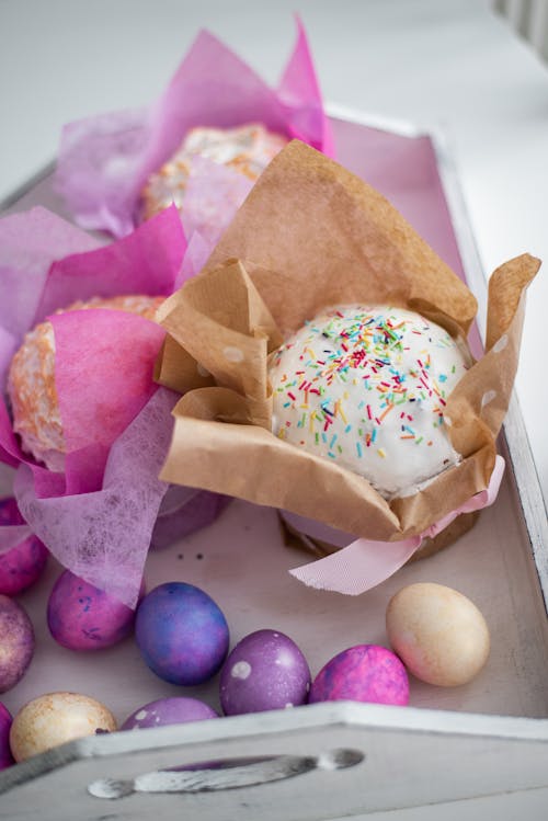 Easter box with delicious decorated cakes and scattered multicolored eggs