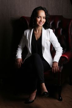 一位自信的女商人坐在高档办公室里，散发着专业精神和风格