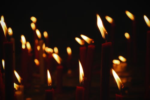 Red burning candles lighting on dark street during religious holiday at night