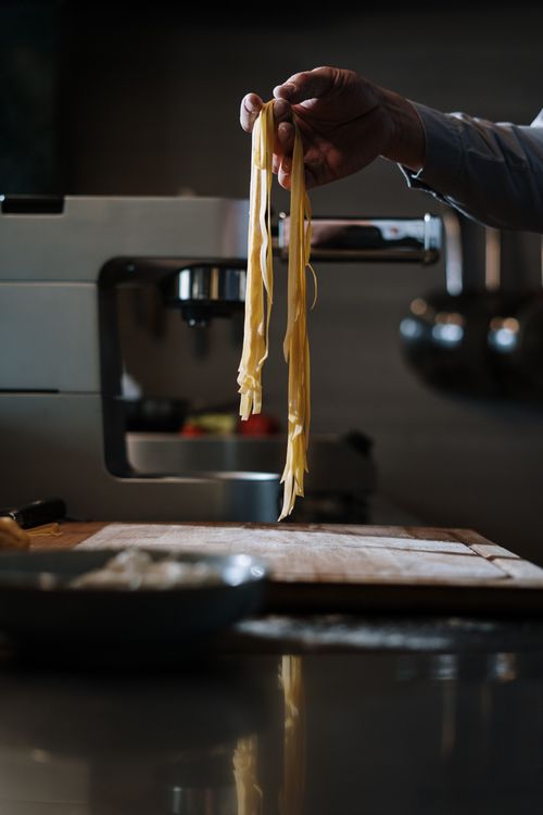 Free A chef displays freshly made pasta in a modern kitchen, highlighting culinary craftsmanship. Stock Photo