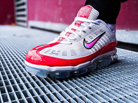 Close-up of a red and white Nike sneaker on a metal grate, showcasing modern footwear design.