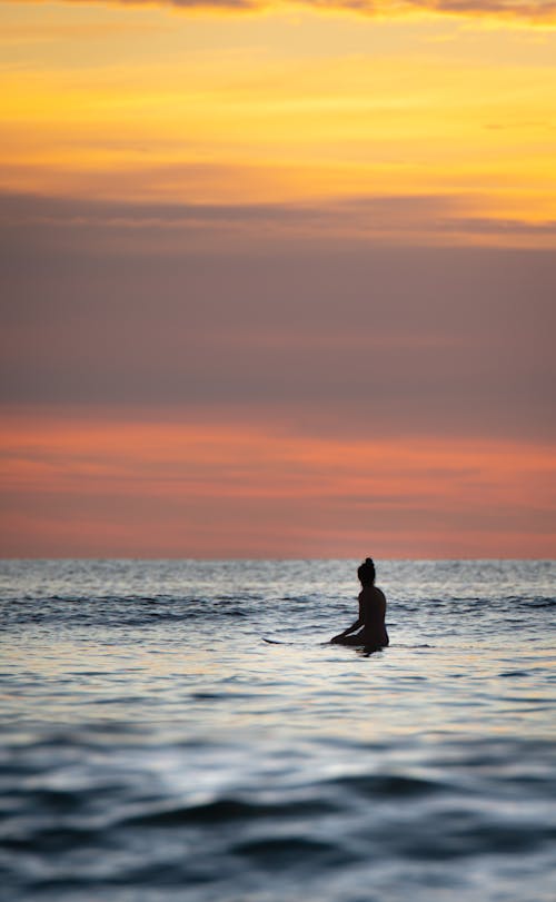 Free Silhouette of Person on Sea during Sunset Stock Photo