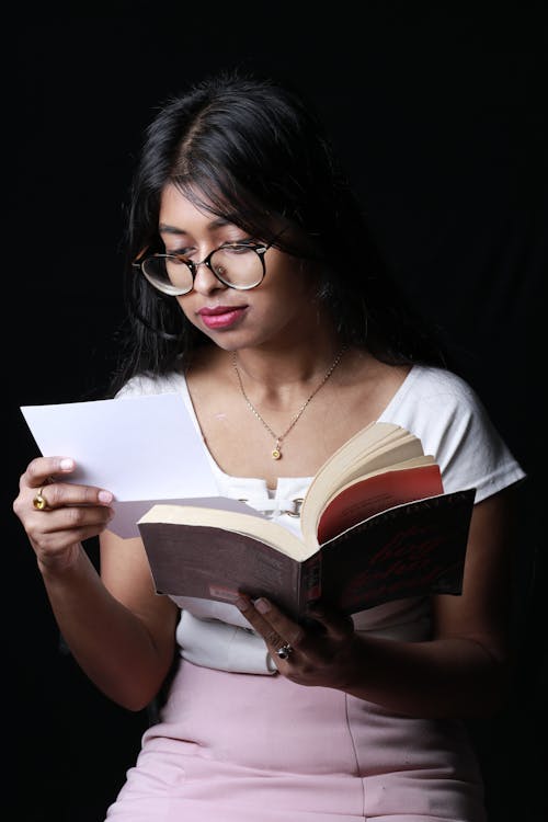 Free Focused young ethnic female student reading textbook Stock Photo
