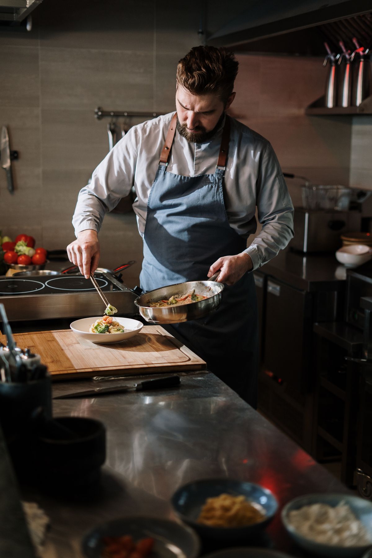 Cook finishing a plate on a stainless bench