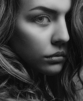 Monochrome close-up portrait of a woman's face with flowing hair, capturing a dramatic expression.