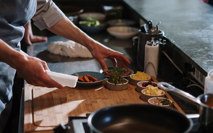 Chef organizing ingredients at a restaurant kitchen counter, ready for cooking.