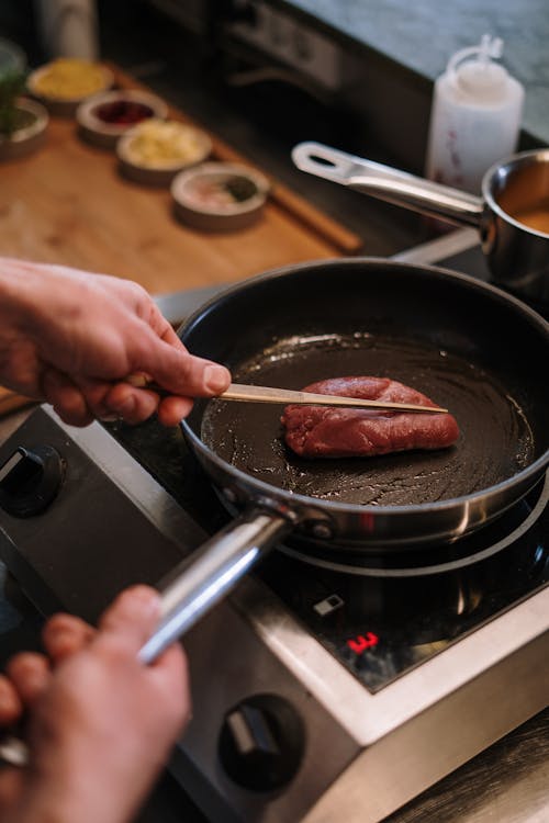 Free Person Cooking Meat on Black Pan Stock Photo